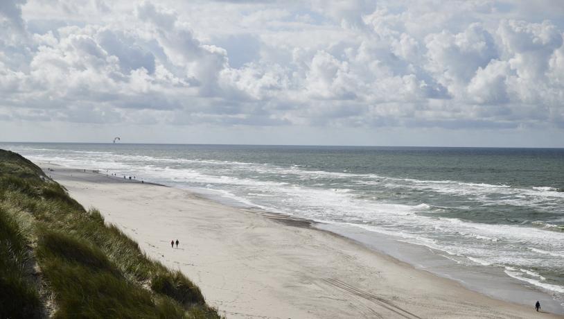 Kyst med mennesker gående på stranden 