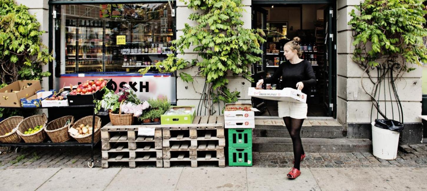 Kvinde med papkasse i hænderne på vej ud af butik på Vesterbro i København