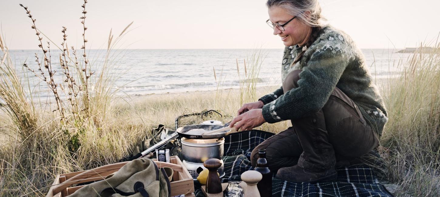 Kvinde er ved at lave mad på trangia 