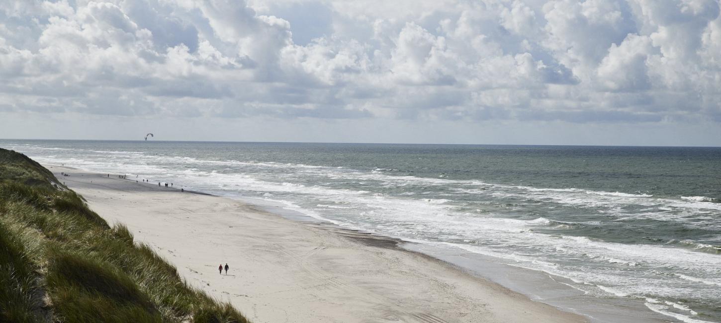 Kyst med mennesker gående på stranden 