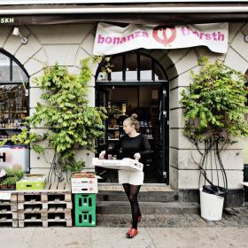 Kvinde med papkasse i hænderne på vej ud af butik på Vesterbro i København